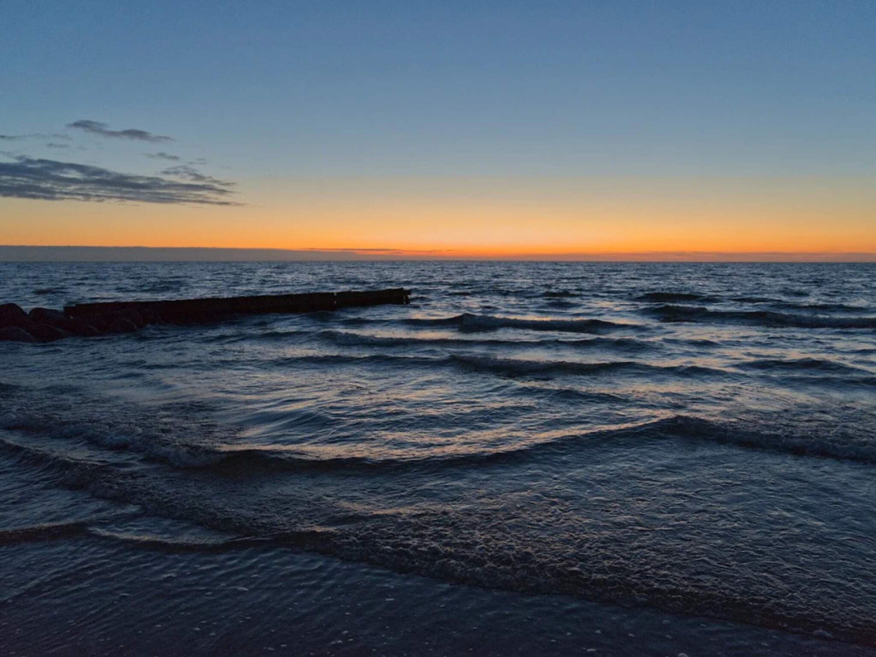 A coastal scene with waves and a sunset.