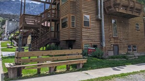 A wooden building with multiple windows and balconies, a wooden bench, and a sign indicating it is for sale. - Walk to Downtown! 2-bedroom with mountain views (Ouray)
