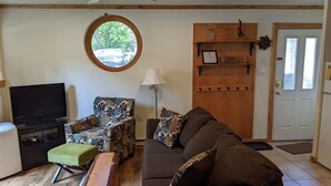 A living room with a television, patterned sofa, ottoman, and a wooden bench. - Walk to Downtown! 2-bedroom with mountain views (Ouray)