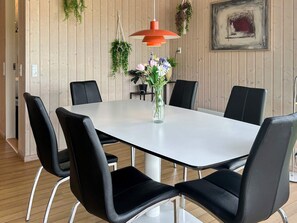 A dining area with a white table, black chairs, a hanging macrame plant, and a red pendant light. - 4 Star Holiday Home in Bjert (Bjert)