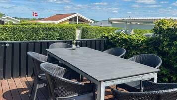 An outdoor patio with a table and chairs, a bottle of wine, and a flag.