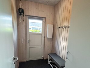 A narrow hallway with a door, a bench, and a wall-mounted coat rack. - 4 Star Holiday Home in Bjert (Bjert)