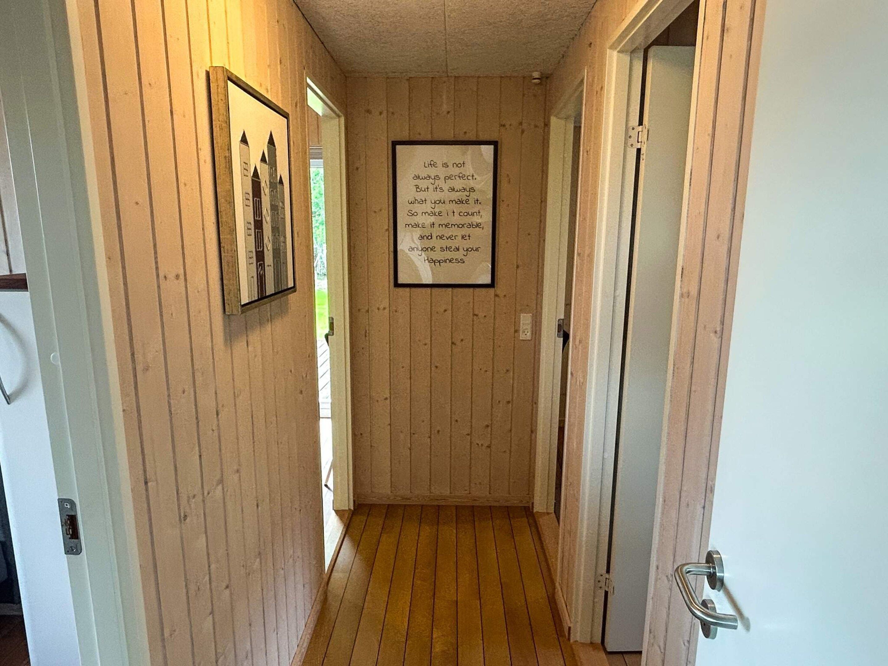 A wooden-paneled hallway with a framed inspirational quote on the wall.