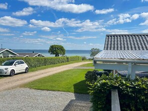 A coastal property with a gravel driveway, a white car parked, and a view of the sea.