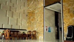 Un hall d’entrée doté d’un sol en marbre, de meubles en bois et d’un mur orné de motifs.