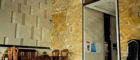A lobby with a marble floor, wooden furniture, and a patterned wall.