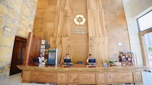 Un comptoir d’accueil avec un panneau arrière en bois et le logo de l’hôtel South America Holiday.