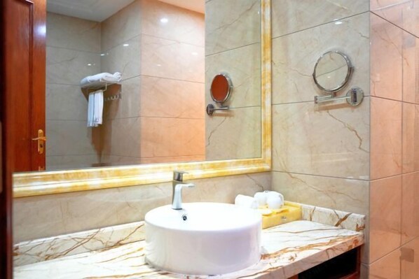 Une salle de bain avec un lavabo en marbre, un miroir et un porte-serviettes.