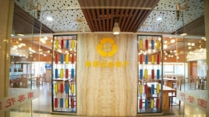 Un intérieur moderne avec un pilier central en bois, des cloisons en verre et des luminaires suspendus.