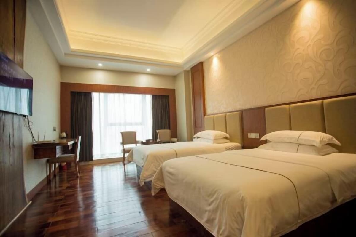 A hotel room with two beds, a desk, and a chair.