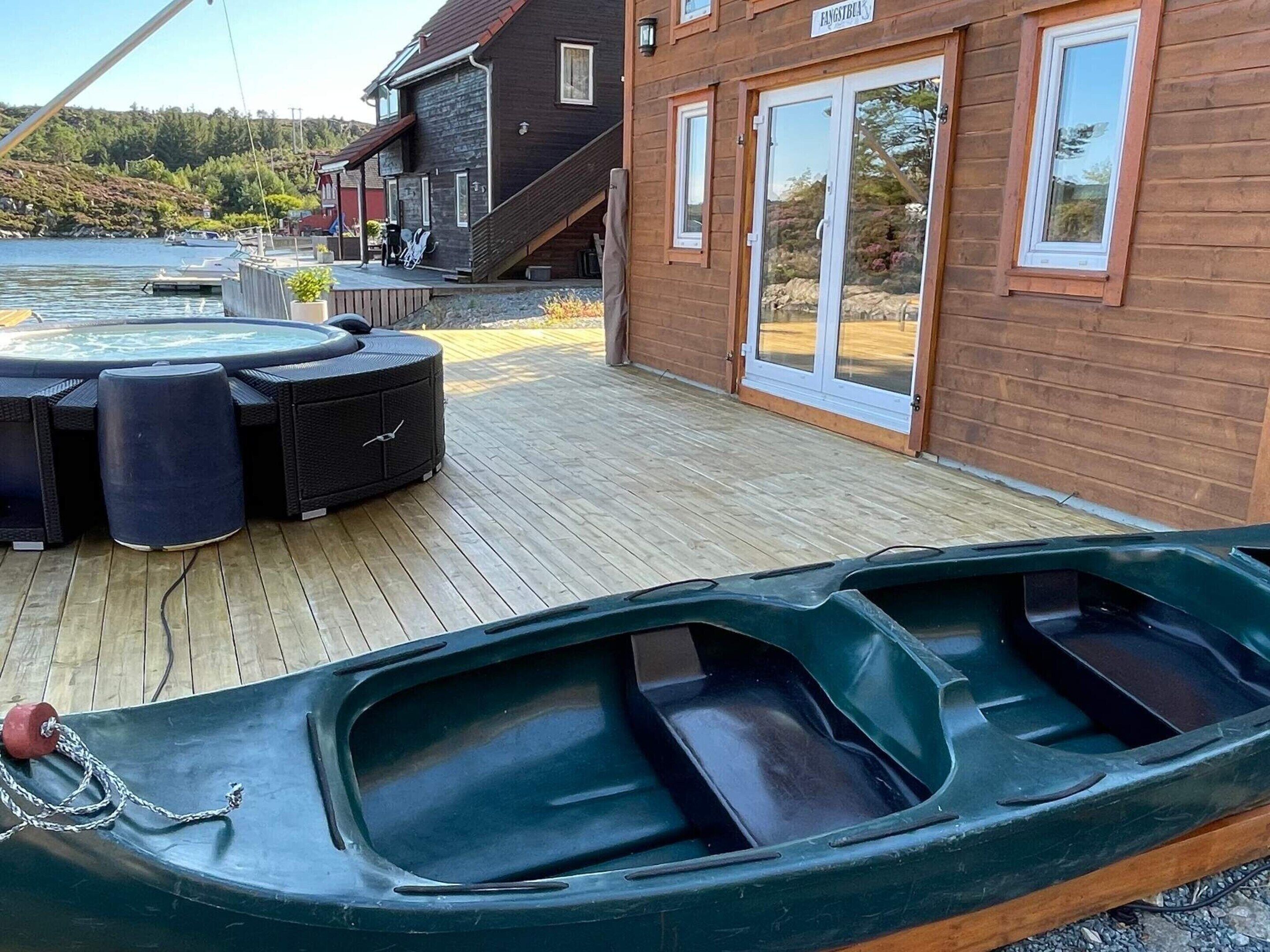 A wooden deck with a hot tub, outdoor seating, and a boat.