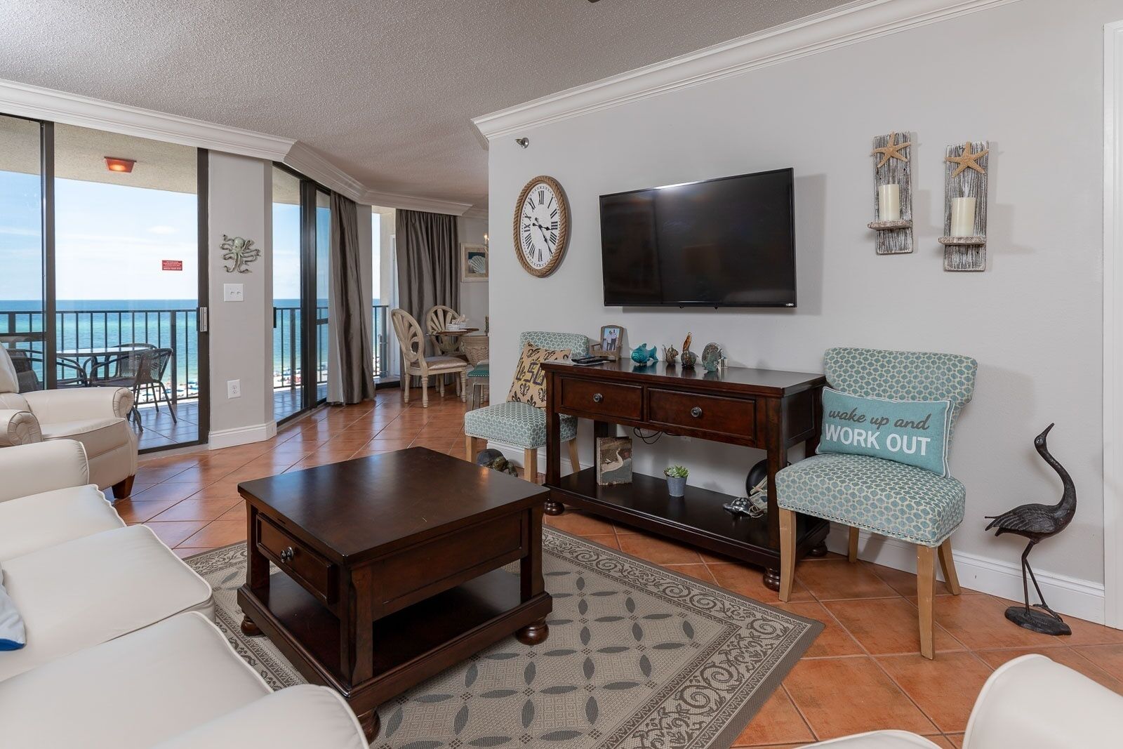 A living room with a large TV, a coffee table, and two patterned chairs.