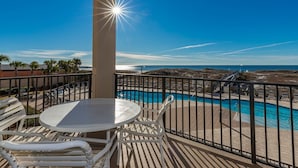 Un balcon avec vue sur une piscine et l’océan.