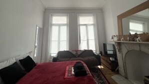 A room with a bed, a fireplace, and a large mirror.