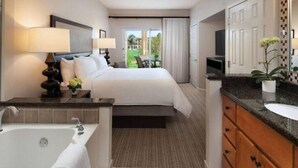 Een hotelkamer met een groot bed, een aparte badkamer met bad, wastafel en spiegel.