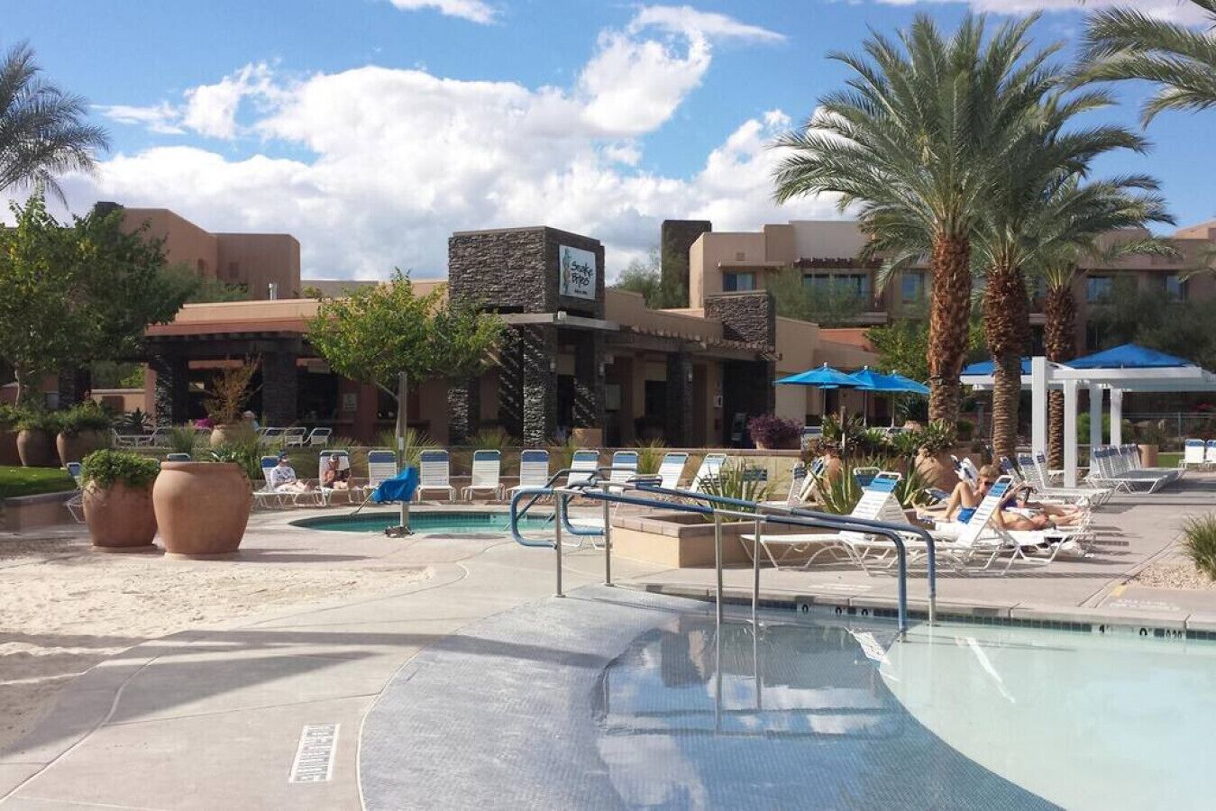 A pool area with lounge chairs and palm trees.