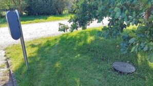 Un jardín con un cartel metálico y una tapa redonda de alcantarilla.