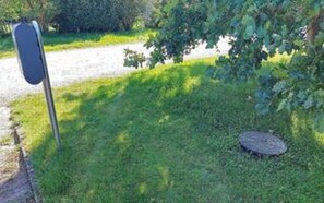 A garden with a metal signpost and a circular manhole cover.
