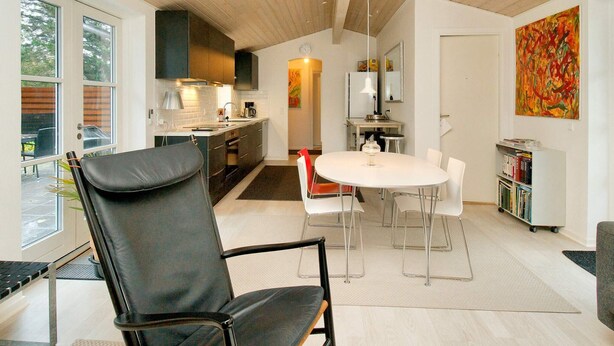 A modern kitchen with dark cabinets, a white countertop, and a dining area with a round table and chairs.