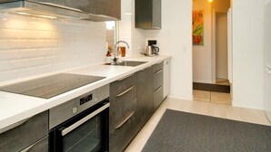 A modern kitchen with dark cabinets, white countertops, and a built-in oven.