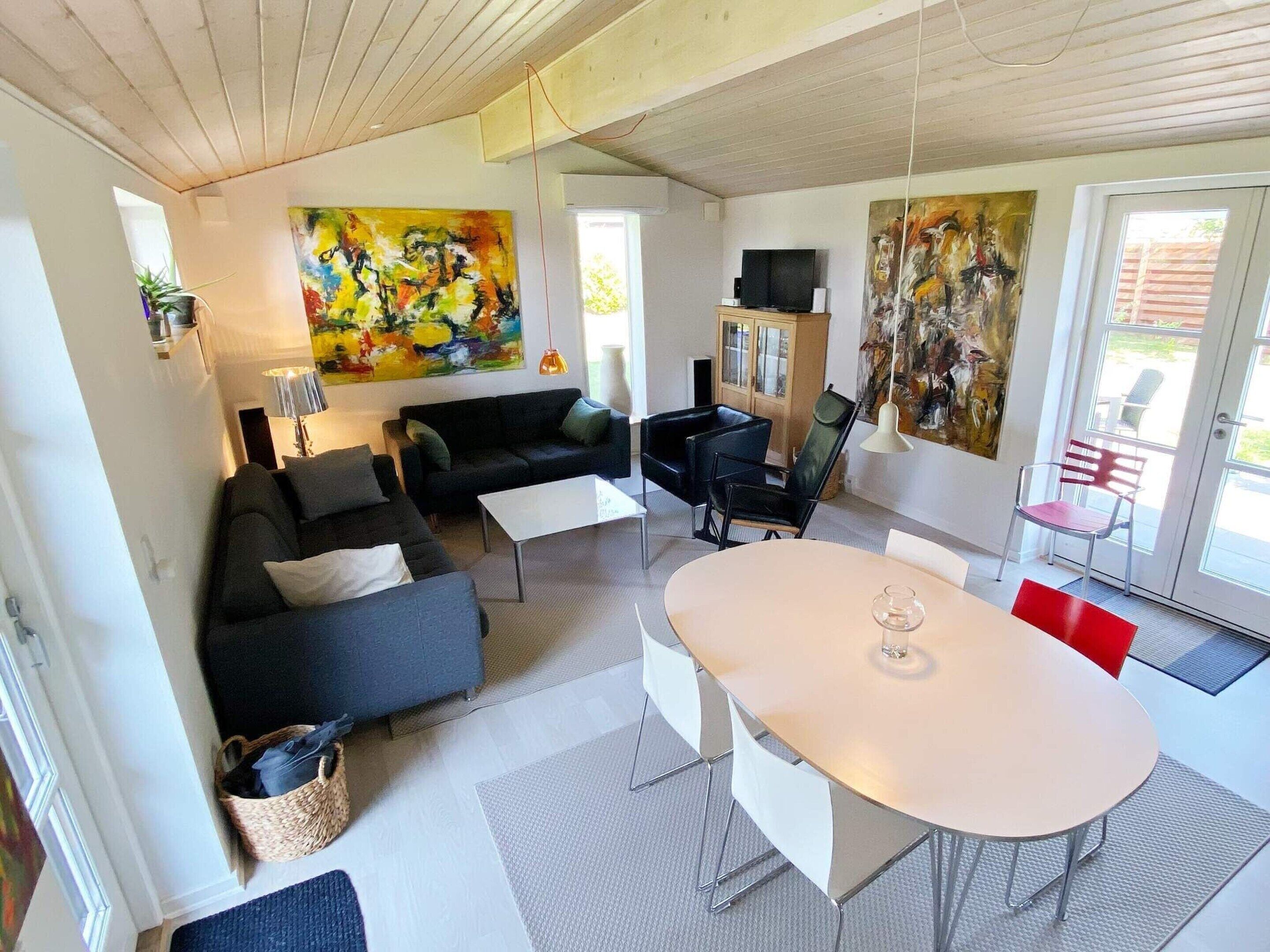 A modern living room with a sofa, a dining table, and two paintings.