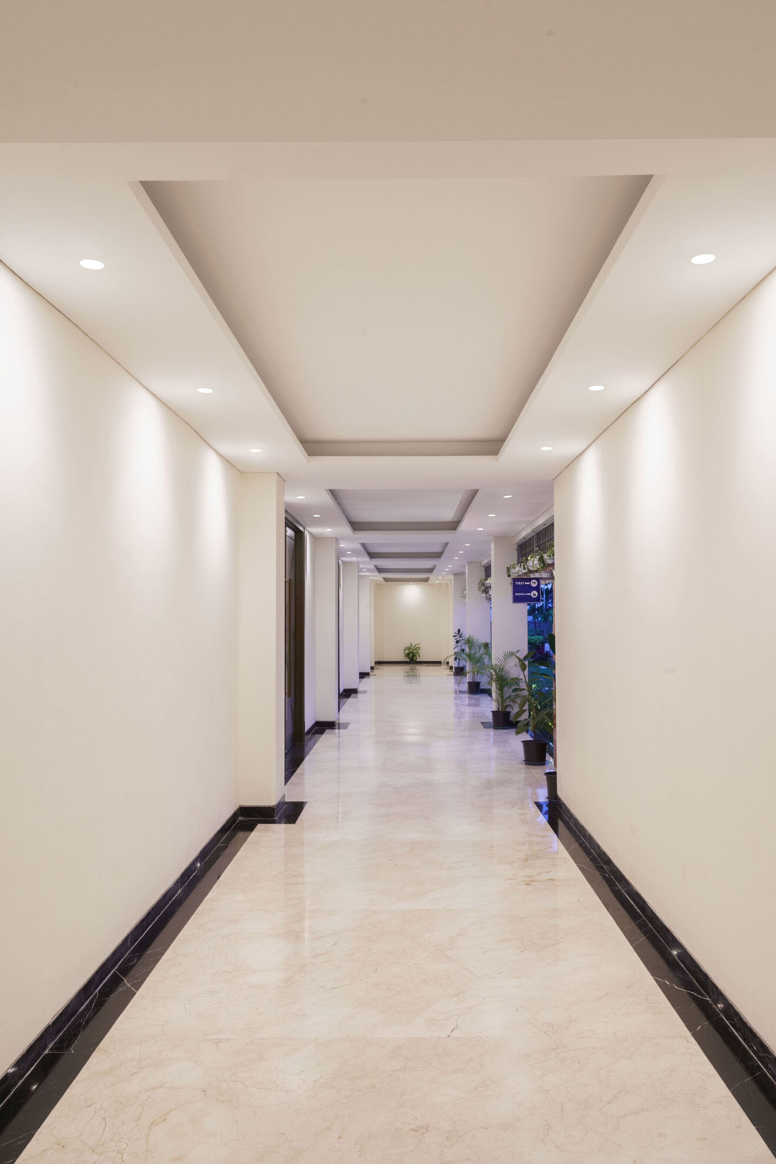 A long, well-lit corridor with a marble floor and modern lighting fixtures.