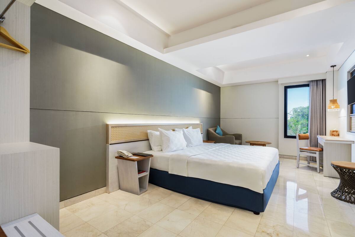A modern hotel room with a large bed, bedside tables, a desk, and a chair.