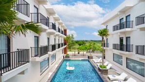 A modern hotel with a swimming pool, balconies, and outdoor seating.