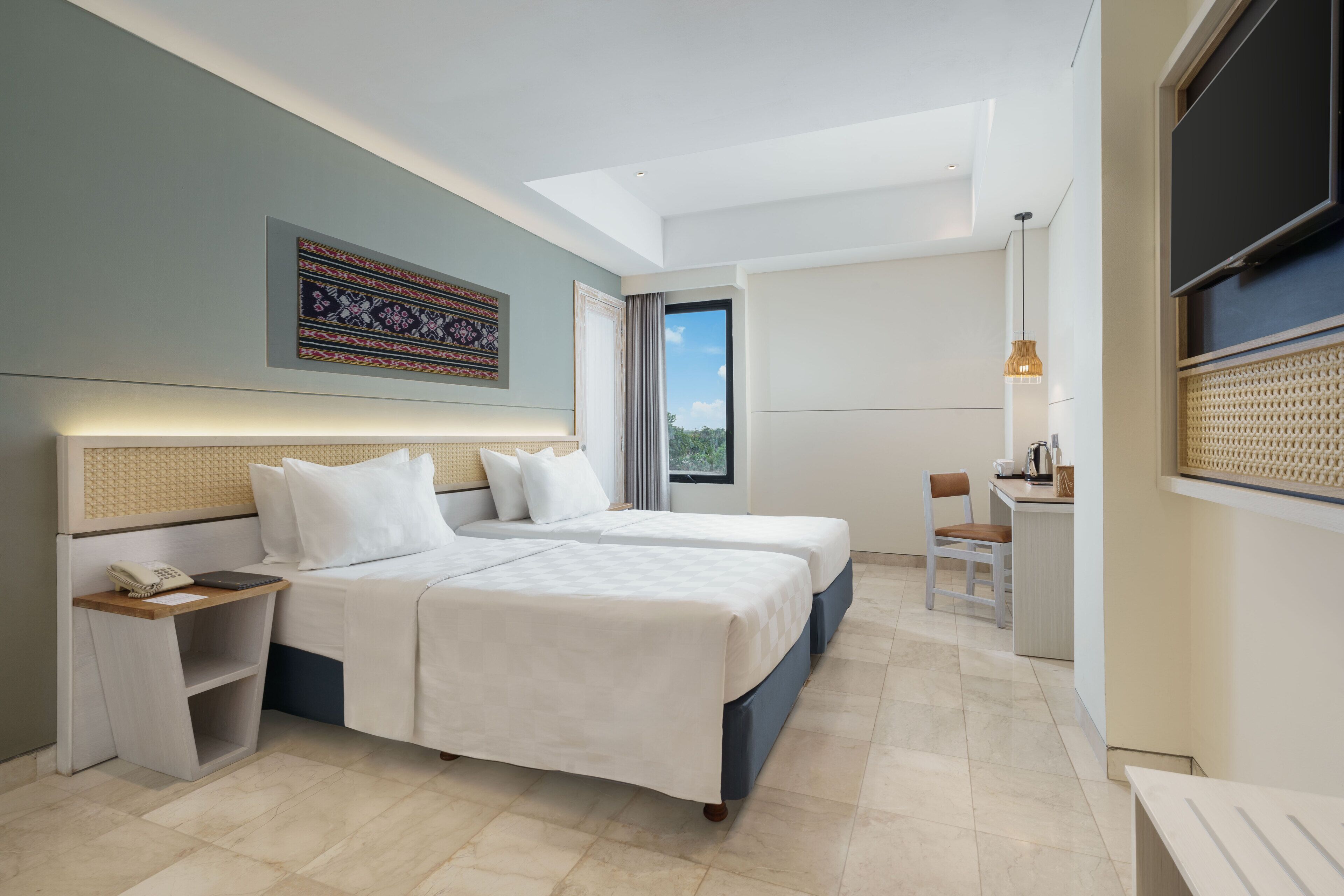 A modern hotel room with two beds, a desk, and a large window offering a view.