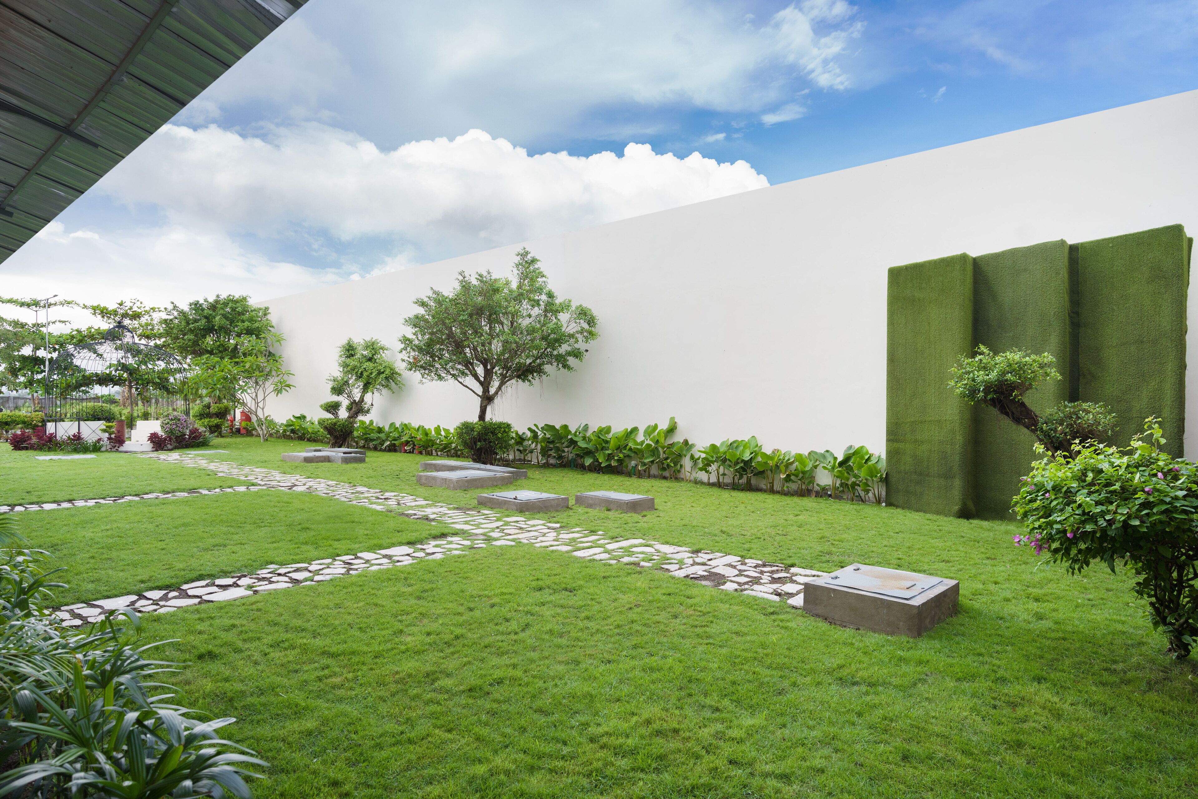 Een verzorgde tuin met een pad van stenen, groene hagen en verschillende planten.