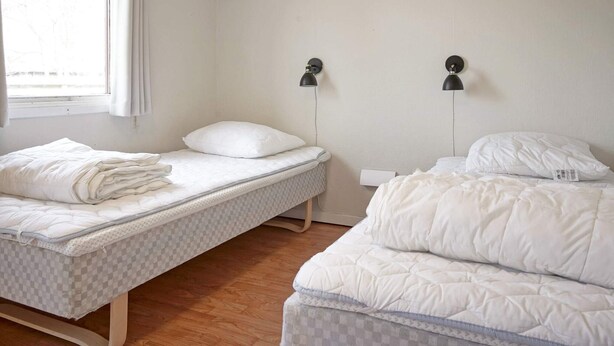 A room with two beds, a window with curtains, and two wall-mounted lamps. - 7 Person Holiday Home in Nexo (Nexø)
