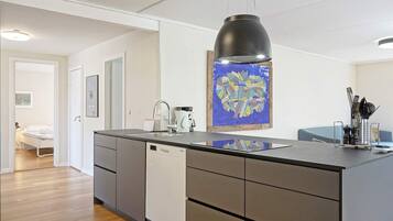 Una cocina moderna con una isla central, una lámpara colgante y una obra de arte colorida en la pared.