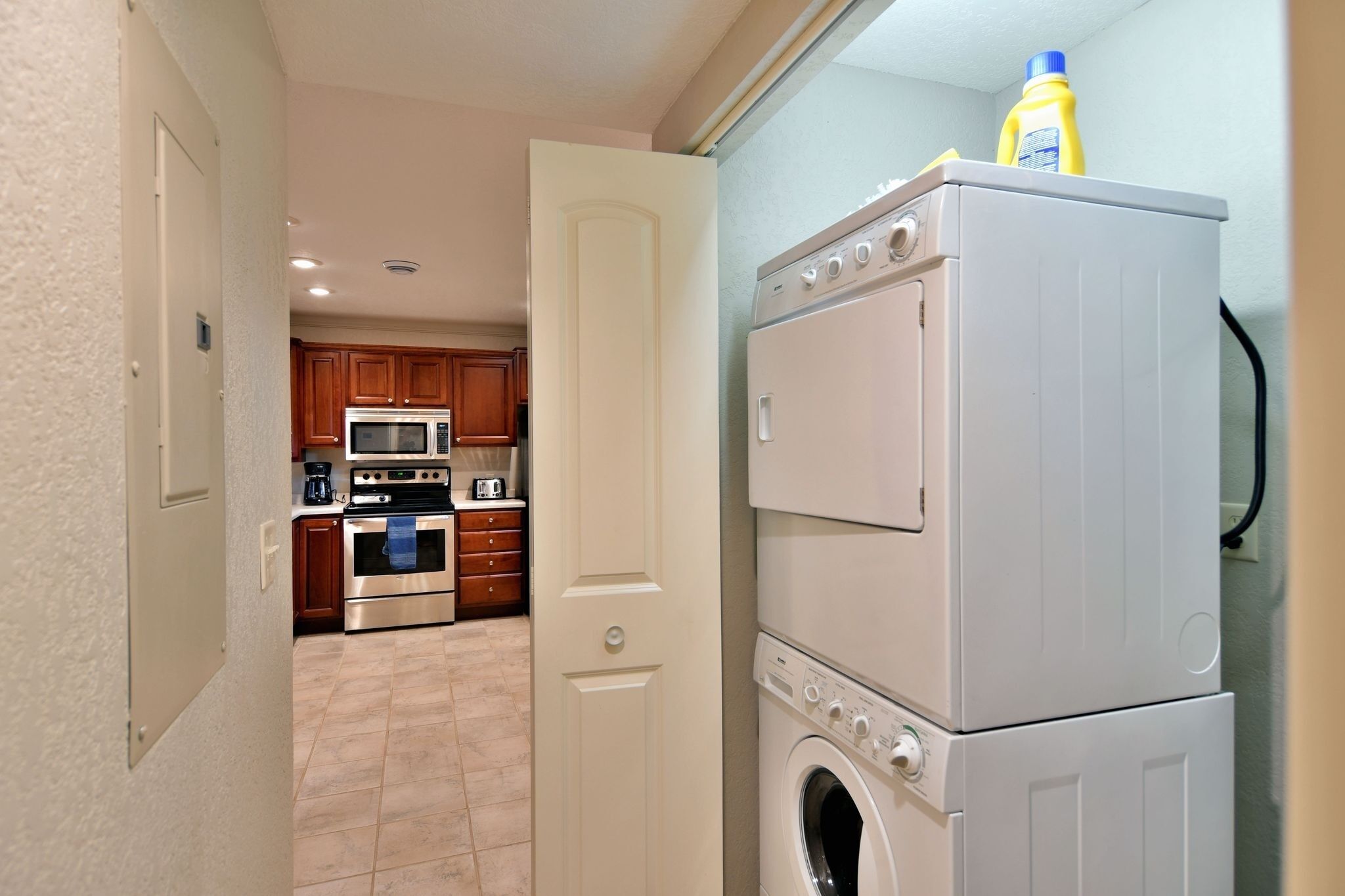 A laundry area with stacked washers and dryers, a microwave, and a stove.