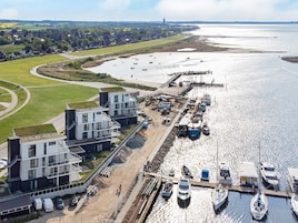 Vista aérea de una zona costera con edificios modernos, un puerto deportivo y un río.