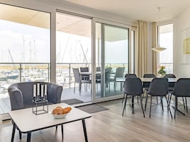 Una sala de estar moderna con un balcón con vista a un puerto deportivo.