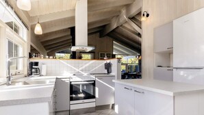 A modern kitchen with white cabinetry, a built-in oven, and a large window providing natural light. - 6 Person Holiday Home in Hals-by Traum (Hals)