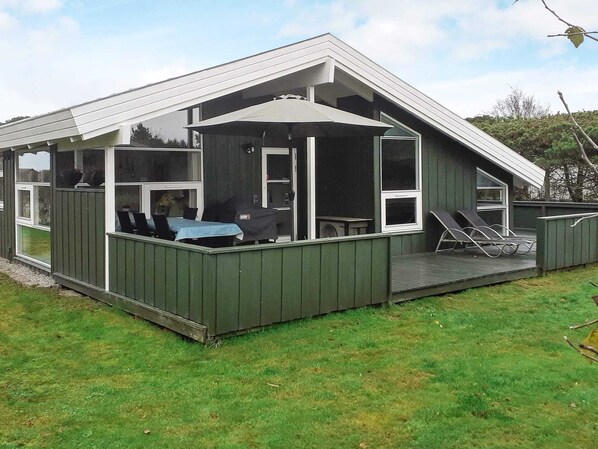 A modern house with a covered patio area, a dining table, and outdoor seating.
