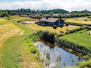 A rural house with a pond, surrounded by green fields and trees. - 5 Star Holiday Home in Rudkobing (Rudkobing)