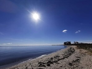 A beach with a clear sky and the sun shining.