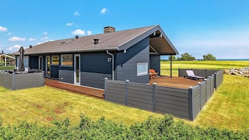 A modern house with a deck, a covered patio, and a number 27 sign.