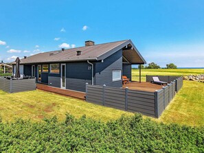 A modern house with a deck, a covered patio, and a number 27 sign.