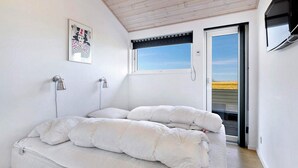 Une chambre à coucher avec un lit, une fenêtre, une porte et un téléviseur fixé au mur.