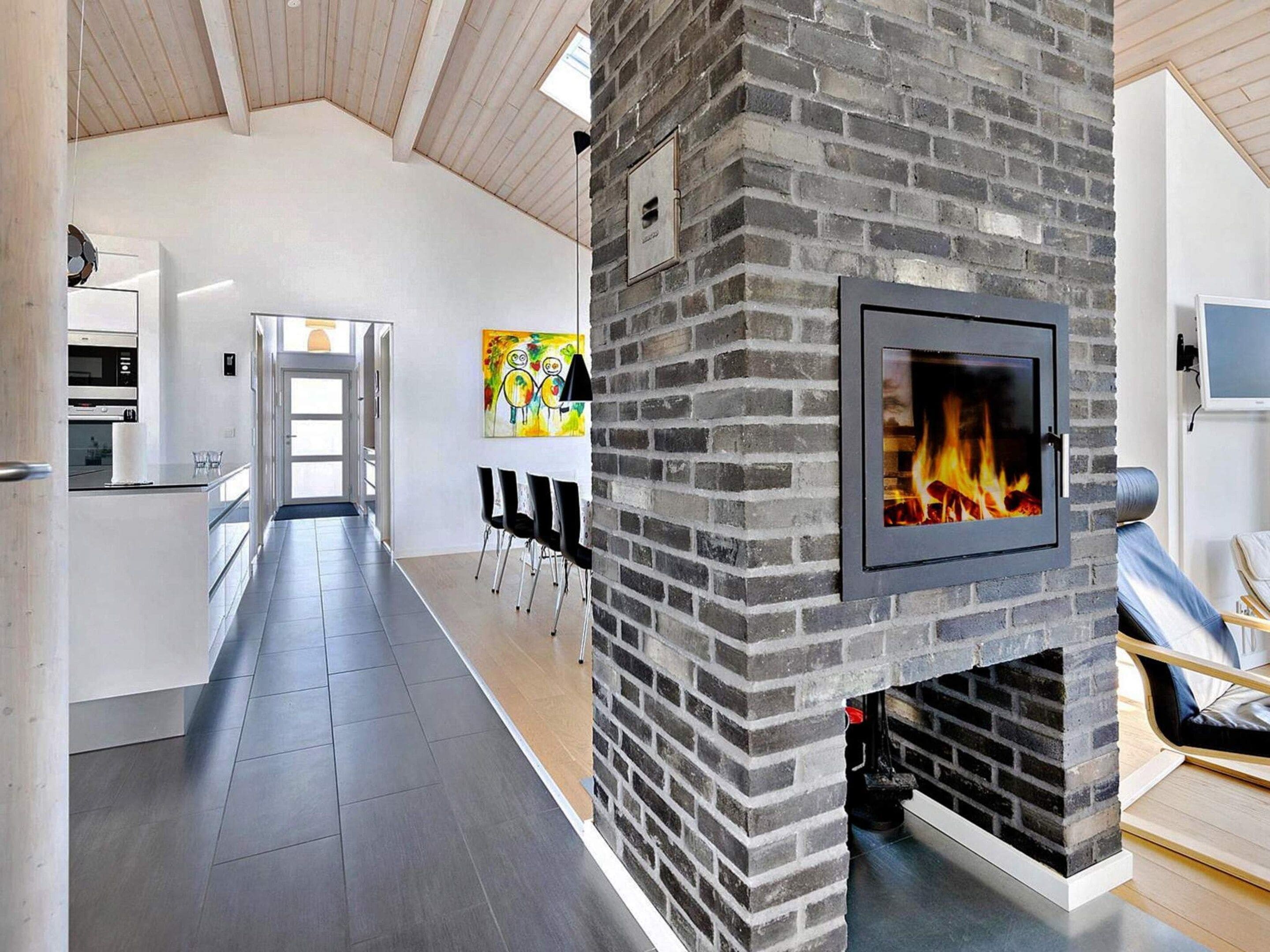 A modern kitchen with a built-in oven, a dining area with chairs, and a fireplace.