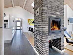 A modern kitchen with a built-in oven, a dining area with chairs, and a fireplace.