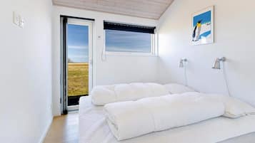 A bedroom with a bed, a window with a view, a painting, and a door leading outside.