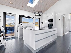 A modern kitchen with a large island, built-in appliances, and a view of the outdoors. - 5 Star Holiday Home in Rudkobing (Rudkobing)