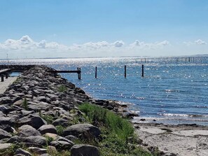 A rocky shoreline with a pier extending into calm waters, under a clear sky. - 5 Star Holiday Home in Rudkobing (Rudkobing)