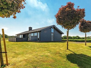 A modern house with a sloped roof, large windows, and a fenced yard.