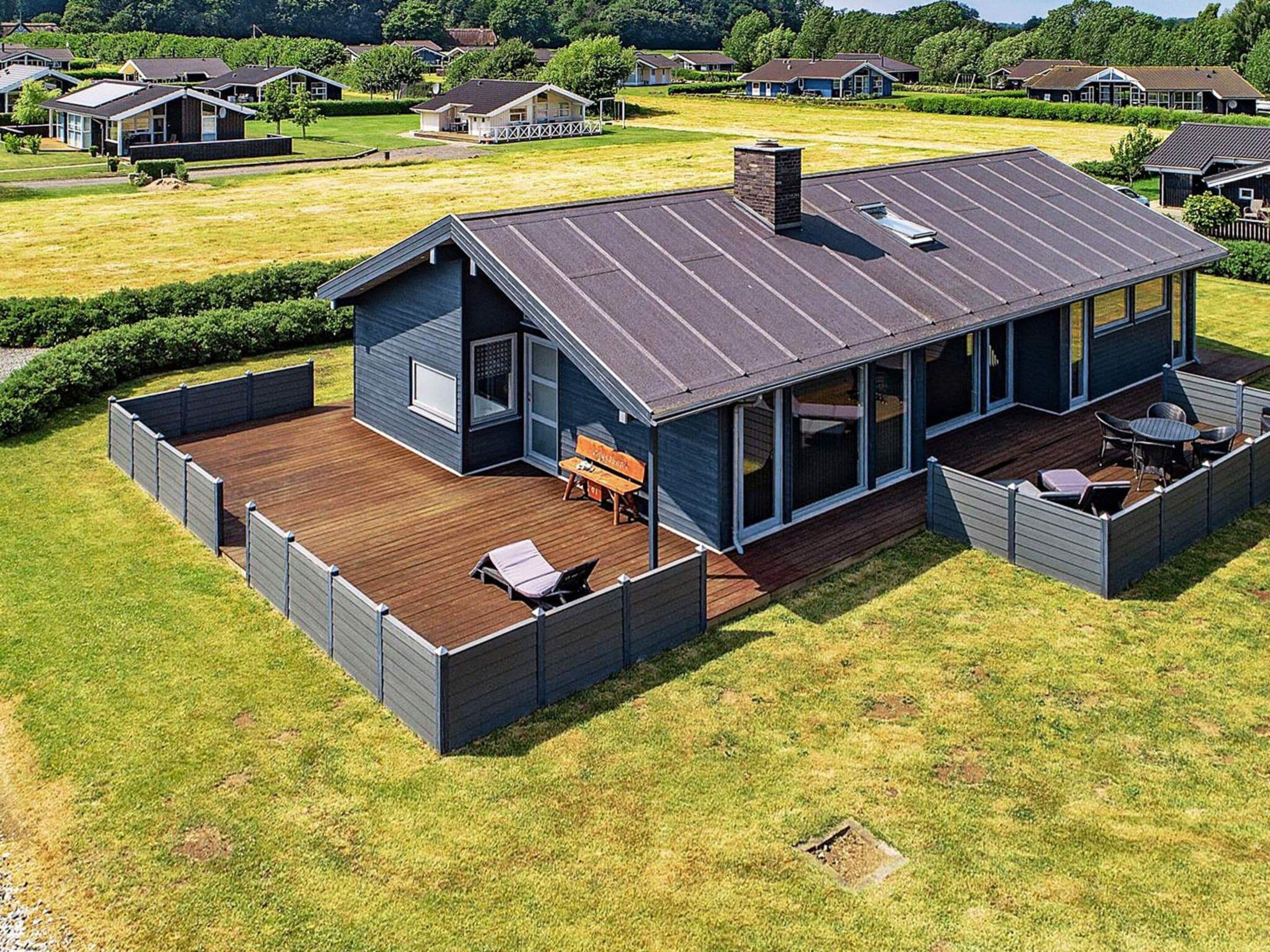 A modern house with a deck, large windows, and a chimney.