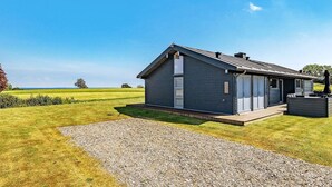 Une maison moderne avec un toit en pente, de grandes fenêtres et une allée gravillonnée.